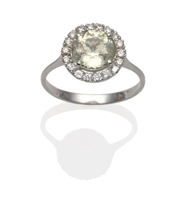 Lot 2025 - A Pale Yellow Sapphire and Diamond Cluster Ring, a round cut sapphire within a border of round...