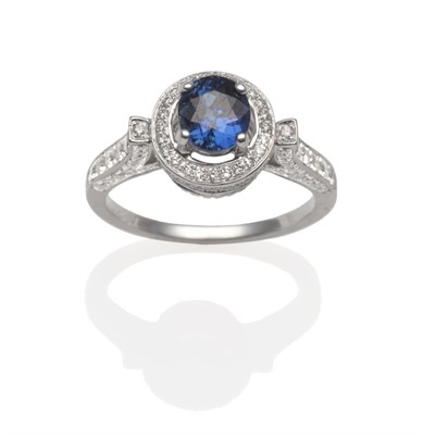 Lot 2027 - A Sapphire and Diamond Cluster Ring, an oval cut sapphire in a white four claw setting within a...