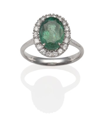 Lot 2029 - An 18 Carat White Gold Emerald and Diamond Cluster Ring, an oval cut emerald within a border of...