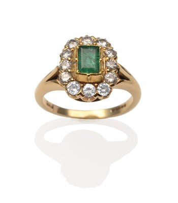 Lot 2091 - An 18 Carat Gold Emerald and Diamond Cluster Ring, an emerald-cut emerald in a yellow rubbed...