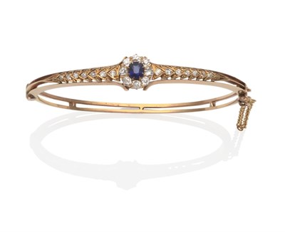 Lot 2109 - A Sapphire and Diamond Bangle, an oval cut sapphire within a border of old cut diamonds, in...