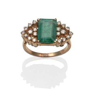 Lot 2127 - An Emerald and Diamond Ring, an emerald-cut emerald in a  yellow claw setting, flanked by an...