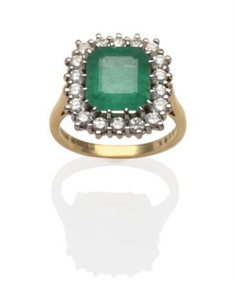 Lot 2144 - An 18 Carat Gold Emerald and Diamond Ring, an emerald-cut emerald within a border of round...