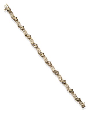 Lot 2153 - A Diamond Bracelet, yellow scroll links channel set with tapering baguette cut diamonds, total...