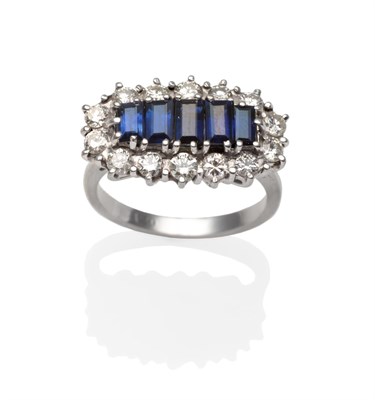 Lot 2172 - A Sapphire and Diamond Ring, with five graduated baguette cut sapphires within a border of...