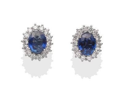 Lot 2173 - A Pair of 18 Carat White Gold Sapphire and Diamond Cluster Earrings, an oval cut sapphire...