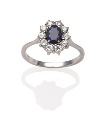 Lot 2174 - An 18 Carat Gold Sapphire and Diamond Cluster Ring, an oval cut sapphire within a border of...