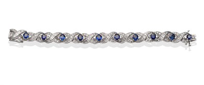 Lot 2179 - A Sapphire and Diamond Crossover Bracelet, oval cut sapphires set with round brilliant cut and...