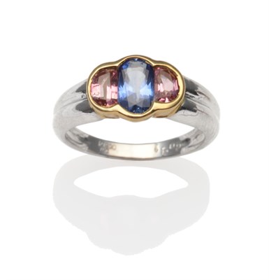 Lot 2191 - A Multi-Gemstone Ring, an oval cut sapphire, flanked by oval cut pink stones in yellow rubbed...