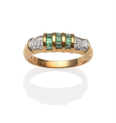 Lot 2193 - An Emerald and Diamond Ring, calibré cut emeralds in yellow channel settings, flanked by white...