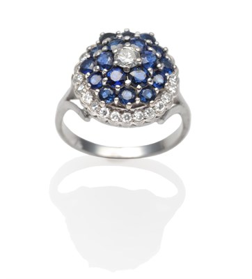 Lot 2223 - A Sapphire and Diamond Cluster Ring, a round brilliant cut diamond within a border of round cut...