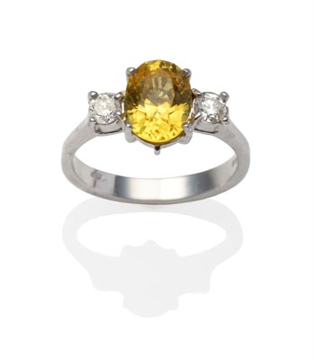 Lot 2228 - An 18 Carat White Gold Yellow Sapphire and Diamond Ring, an oval cut yellow sapphire between...