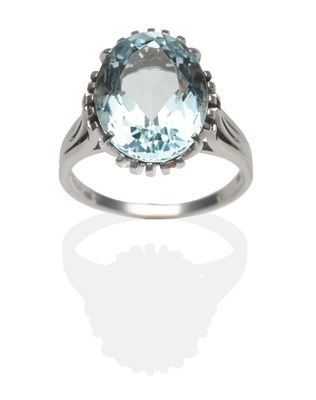 Lot 2024 - An Aquamarine Ring, an oval cut aquamarine in a white claw setting, to forked shoulders on a...