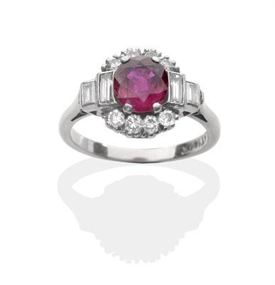 Lot 2043 - A Ruby and Diamond Cluster Ring, a round cut ruby in a white claw setting within a border of...