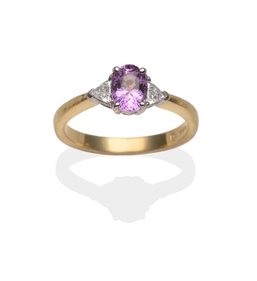 Lot 2057 - An 18 Carat Gold Pink Sapphire and Diamond Three Stone Ring, an oval cut pink sapphire between...