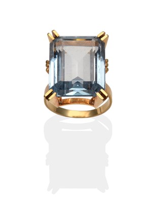 Lot 2085 - A Blue Topaz Ring, an emerald-cut blue topaz in a yellow extended claw setting, to forked shoulders