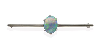 Lot 2119 - A Black Opal Bar Brooch, an oval cut opal in a white claw setting, to a knife edge bar, length...