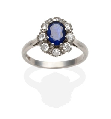 Lot 2138 - A Sapphire and Diamond Cluster Ring, an oval cut sapphire within a border of round brilliant...