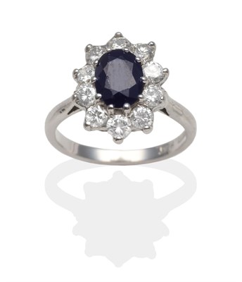 Lot 2140 - A Sapphire and Diamond Cluster Ring, an oval cut sapphire within a border of round brilliant...