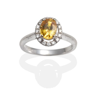 Lot 2032 - An 18 Carat White Gold Yellow Sapphire and Diamond Cluster Ring, an oval cut yellow sapphire in...