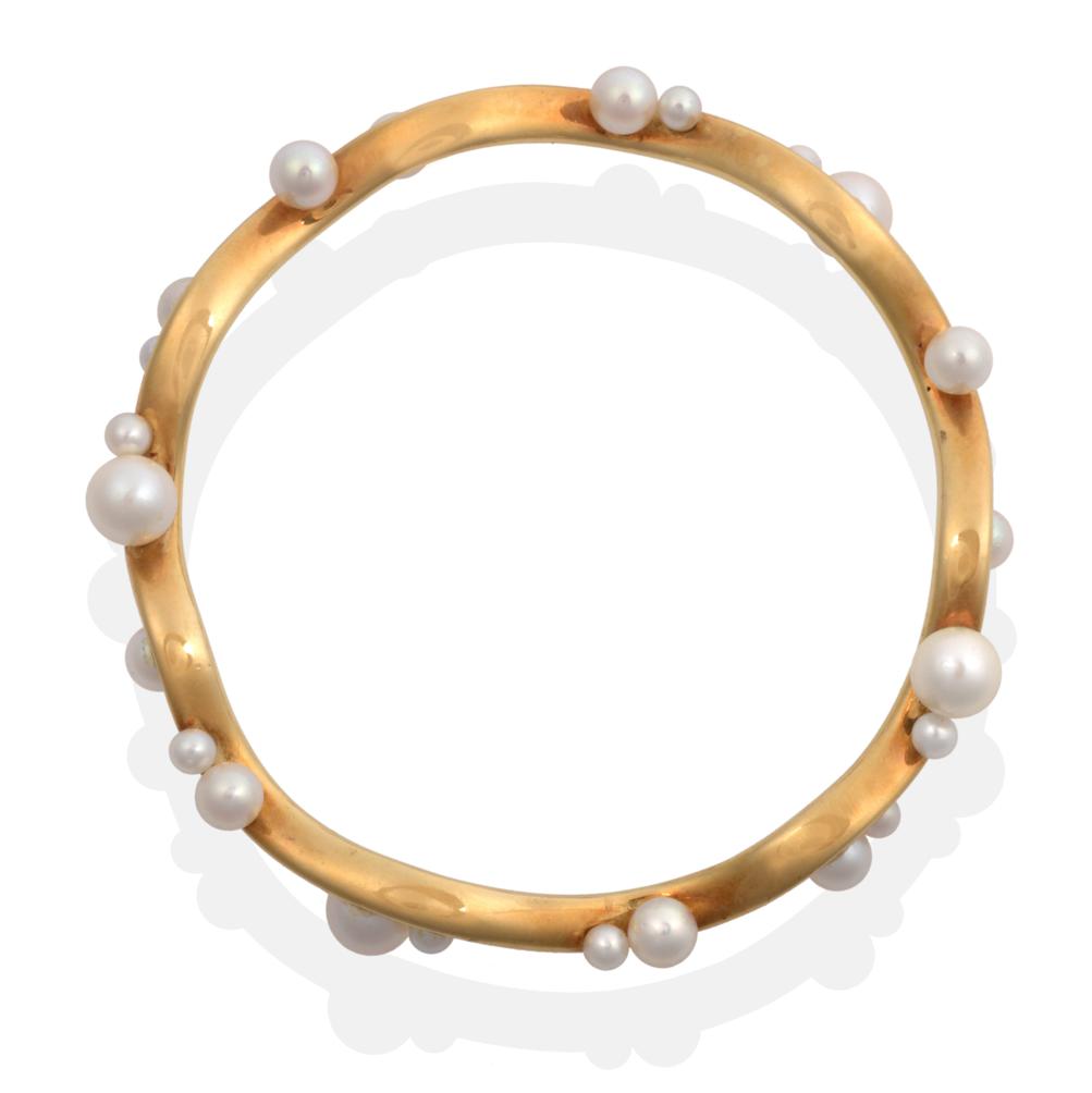 Lot 2064 - An 18 Carat Gold Cultured Pearl Bangle, an undulating bangle set throughout with vari-sized...