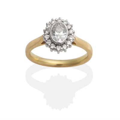 Lot 2073 - An 18 Carat Gold Oval Diamond Cluster Ring, an oval brilliant cut diamond in a rubbed over...