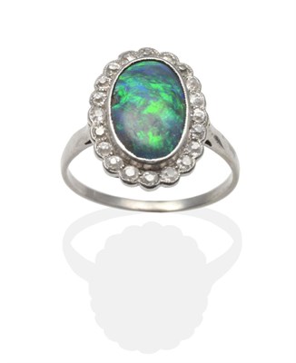 Lot 2120 - A Black Opal and Diamond Cluster Ring, an oval cabochon black opal within a border of old cut...