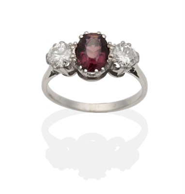 Lot 2121 - A Garnet and Diamond Three Stone Ring, an oval cut garnet between round brilliant cut diamonds...