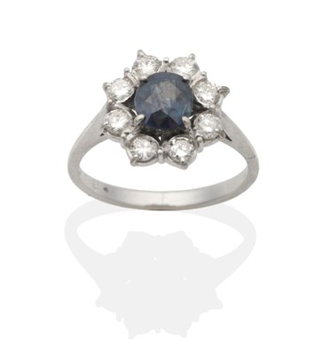 Lot 2150 - A Sapphire and Diamond Cluster Ring, a round cut sapphire within a border of round brilliant...