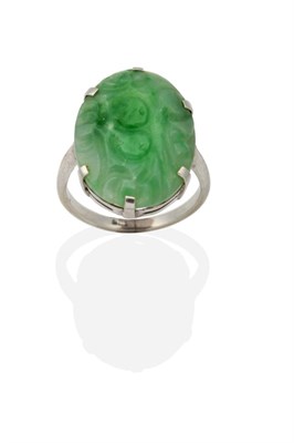 Lot 2003 - A Jade Ring, an oval jade plaque with carved floral decoration in a claw setting, finger size...