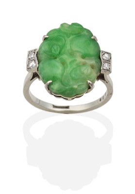 Lot 2029 - An Art Deco Style Jade and Diamond Ring, a carved oval jade plaque in a claw setting to...