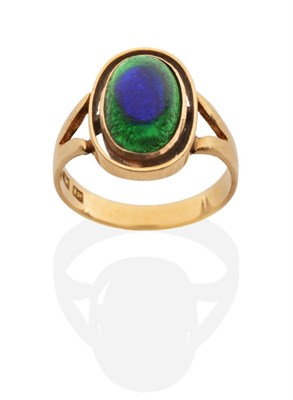 Lot 2054 - A Peacock Glass Ring, an oval glass cabochon in a rubbed over setting within an oval frame, to...