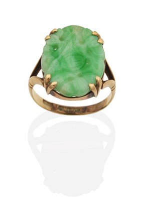 Lot 2063 - A Jade Ring, an oval jade plaque with carved and pierced floral decoration in a double claw...