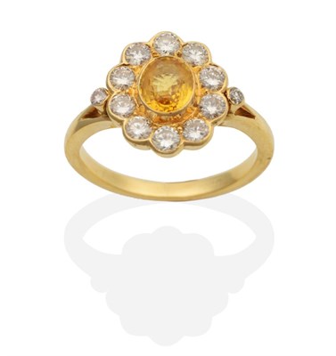 Lot 2113 - A Yellow Sapphire and Diamond Cluster Ring, an oval cut yellow sapphire within a border of...