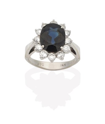 Lot 2142 - A Sapphire and Diamond Cluster Ring, an oval cut sapphire within a border of round brilliant...