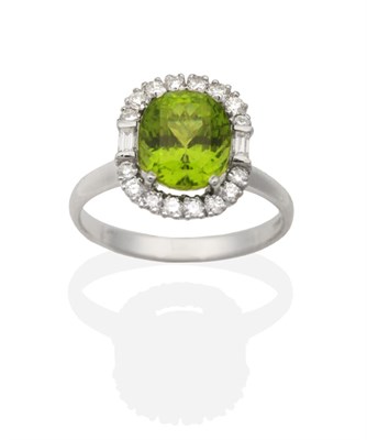 Lot 2147 - An 18 Carat White Gold Peridot and Diamond Cluster Ring, an oval cut peridot in a claw setting...