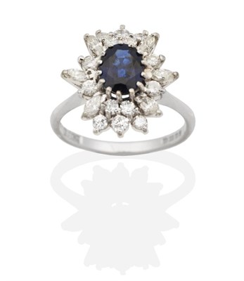 Lot 2148 - An 18 Carat White Gold Sapphire and Diamond Cluster Ring, an oval cut sapphire within a border...