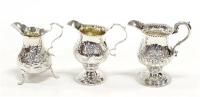 Lot 2234 - Three George III Silver Cream Jugs, comprising: a pedestal example decorated with swags,...