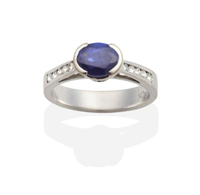 Lot 2014 - A Sapphire and Diamond Ring, an oval cut sapphire in a half rubbed over setting, to tapering...