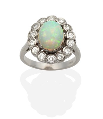 Lot 2019 - An Opal and Diamond Cluster Ring, an oval cabochon opal in a claw setting, within a border of round