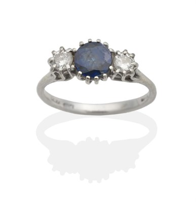 Lot 2037 - An 18 Carat White Gold Sapphire and Diamond Three Stone Ring, a round cut sapphire in a claw...