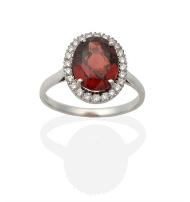 Lot 2044 - An 18 Carat Gold Garnet and Diamond Cluster Ring, an oval cut garnet in a claw setting, within...