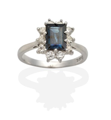 Lot 2148 - An 18 Carat White Gold Sapphire and Diamond Cluster Ring, a baguette cut sapphire in a claw...