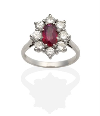 Lot 2157 - A Ruby and Diamond Cluster Ring, an oval cut ruby in a claw setting, within a border of round...