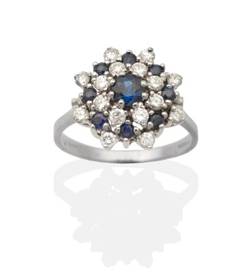 Lot 2178 - An 18 Carat White Gold Sapphire and Diamond Cluster Ring, a round cut sapphire in a claw...