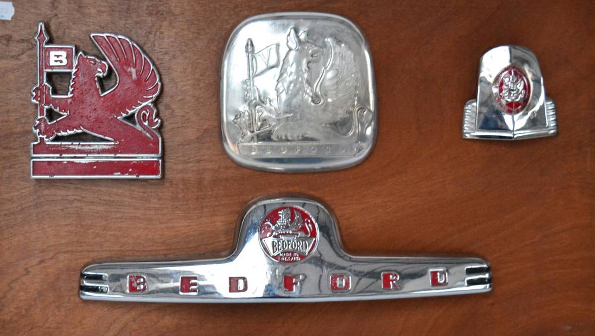 Lot 49 - Four Chromed and Enamel Bedford Motor Vehicle Badges, mounted on a wooden board