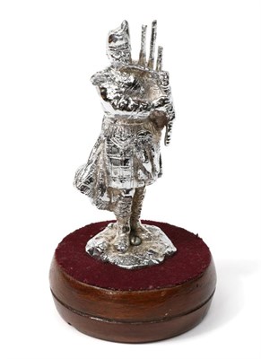 Lot 146 - A Chrome on Brass Car Mascot modelled as a Scottish Piper, playing bagpipes and standing on a rocky