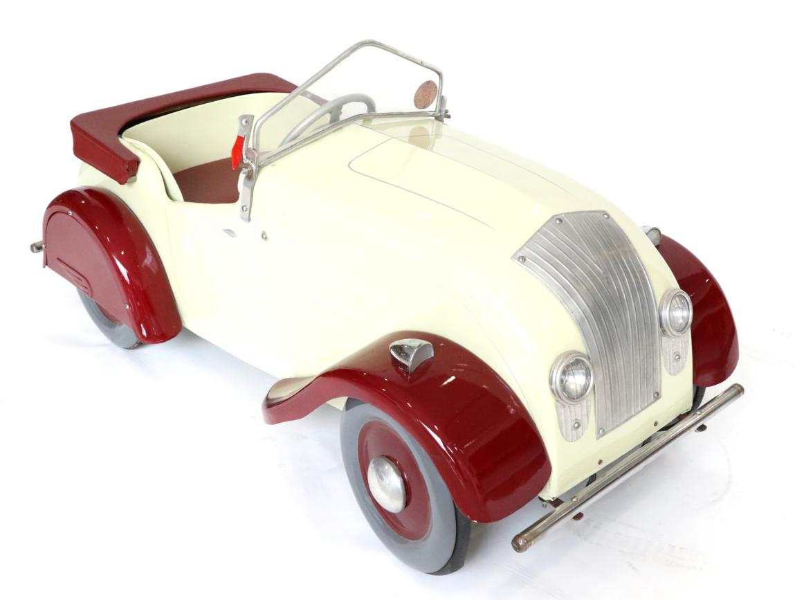 Lot 258 - A 1930s Triang Chrysler Airflow Cream and Red Painted Pedal Car, with metal four-spoke steering...