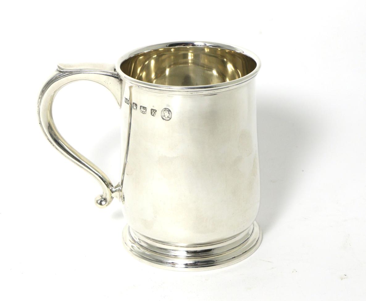 Lot 40 - A Silver Mug, Mappin & Webb, Sheffield 1952, plain on circular foot, with scroll handle, 11.5cm...
