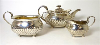 Lot 311 - A matched George III three piece silver tea service, part fluted with gadroon border, on ball feet